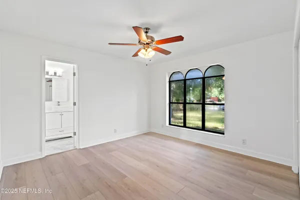an empty room with chandelier fan and windows