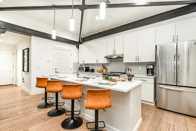 a kitchen with stainless steel appliances granite countertop a sink a stove and chairs with wooden floor