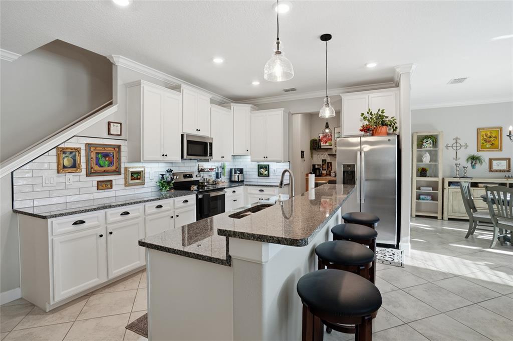 1370 White Fox Run Lutz, FL 33549 - Photo 9 of 49 a kitchen with stainless steel appliances granite countertop a refrigerator a sink dishwasher a dining table and chairs with wooden floor