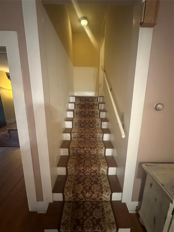 504 1st Street Terrell, TX 75160 - Photo 11 of 27 Wood-finish staircase featuring a patterned runner, white risers, and a light-toned handrail