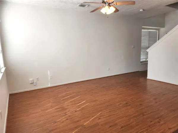 a view of an empty room with wooden floor and a chandelier