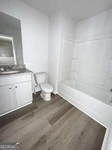 a bathroom with a granite countertop sink a toilet and bathtub