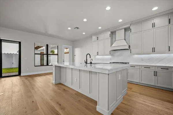 a kitchen with stainless steel appliances granite countertop a sink dishwasher a stove and a refrigerator with wooden floor