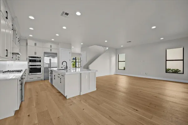 a view of kitchen with kitchen island wooden floor center island and stainless steel appliances