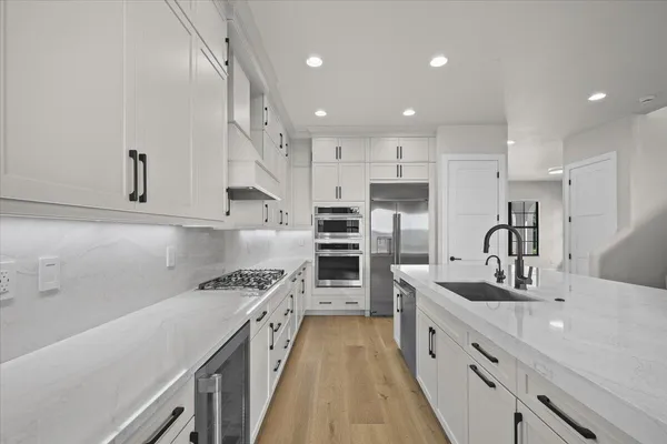 a large white kitchen with kitchen island a sink stainless steel appliances and cabinets