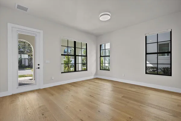 an empty room with wooden floor and windows