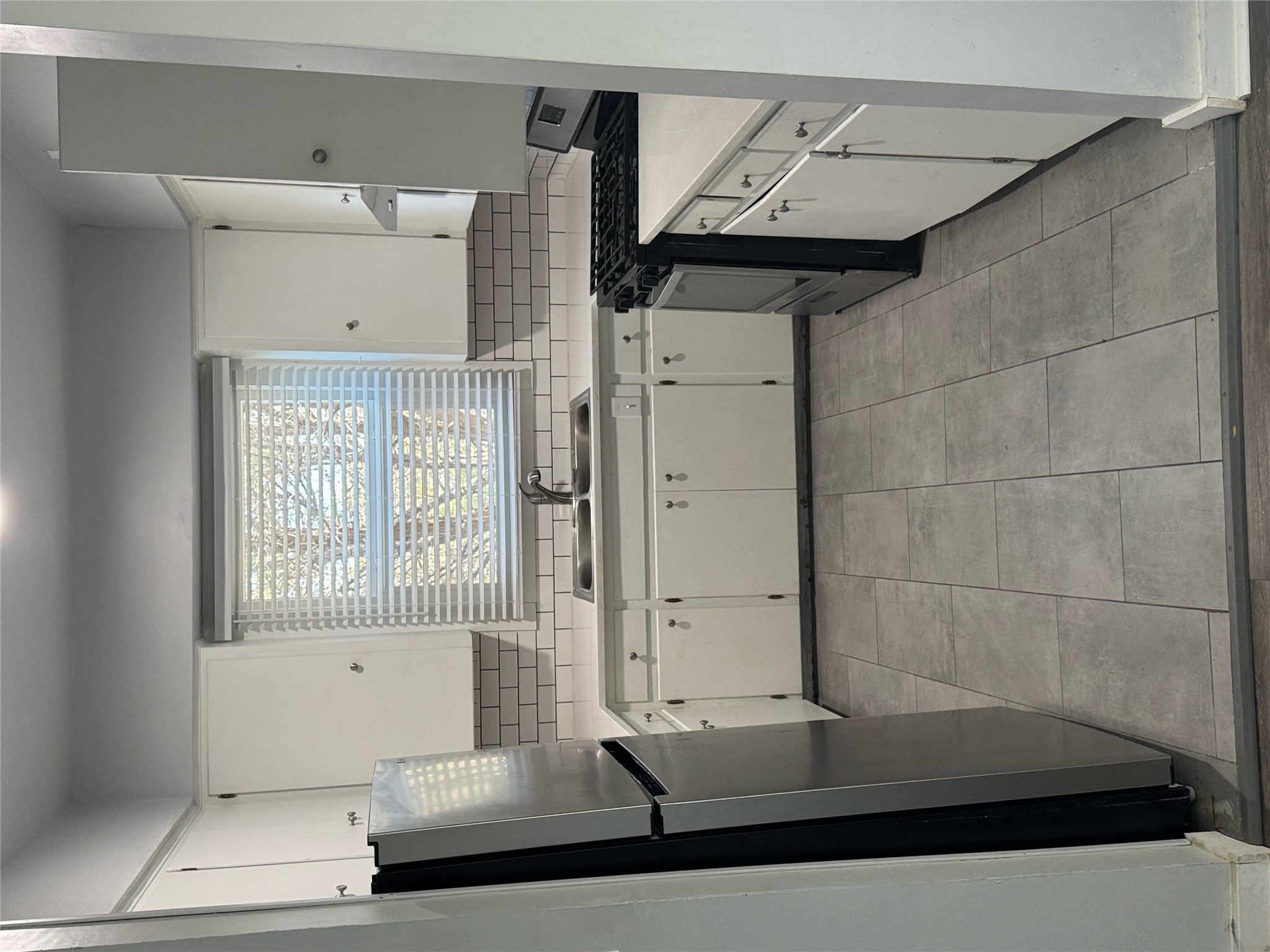 Kitchen featuring gas stove, white cabinetry, freestanding refrigerator, and backsplash