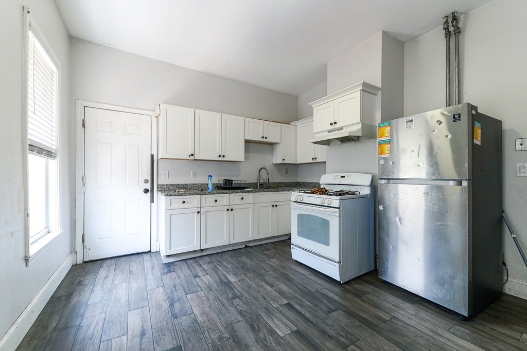 107 Devon Street Boston, MA 02121 - Photo 4 of 9 a kitchen with a refrigerator a white cabinets and wooden floor