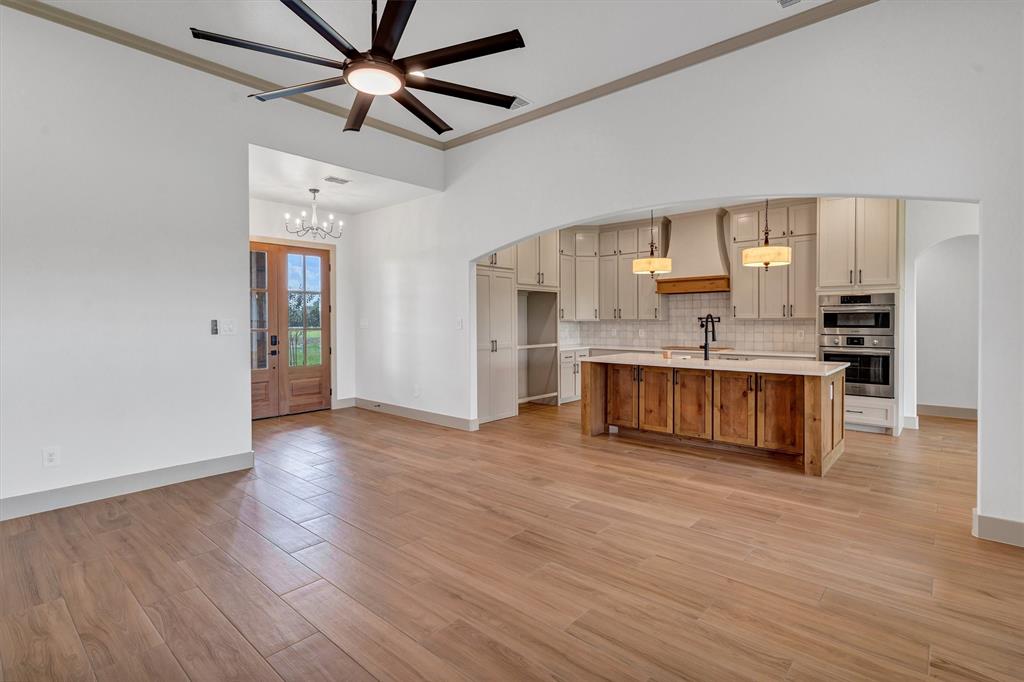 5006 Stover Way Granbury, TX 76049 - Photo 5 of 40 a living room with stainless steel appliances kitchen island hardwood floor and a ceiling fan