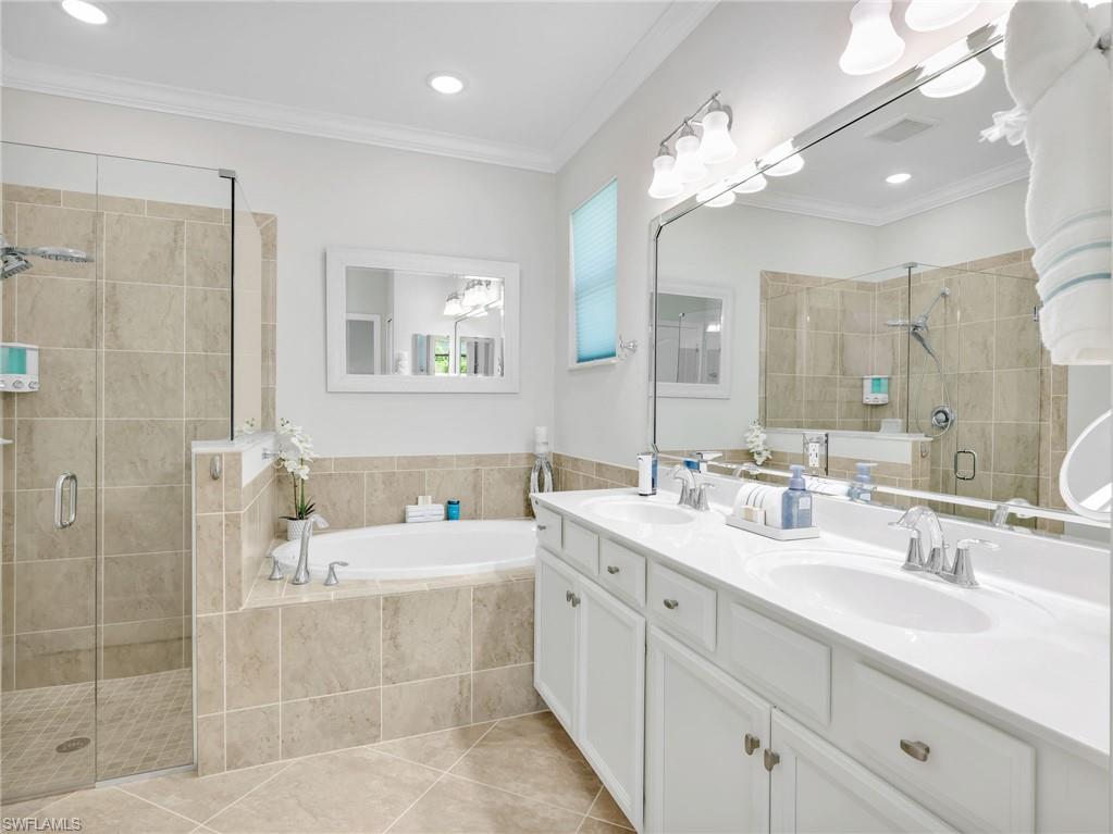 4383 Bismark Way Naples, FL 34119 - Photo 17 of 49 Primary En Suite Bathroom with Crown Molding, Tile Shower with Glass Enclosure & New Shower Head & Separate Handheld, Tiled Soaking Tub, & Large White Shaker Vanity with New Hardware, & Dual Sinks
