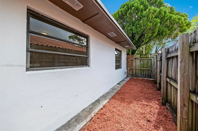 a view of a pathway of a house with backyard and wooden fence
