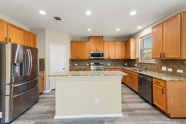 a kitchen with stainless steel appliances granite countertop a refrigerator a stove a sink and a microwave