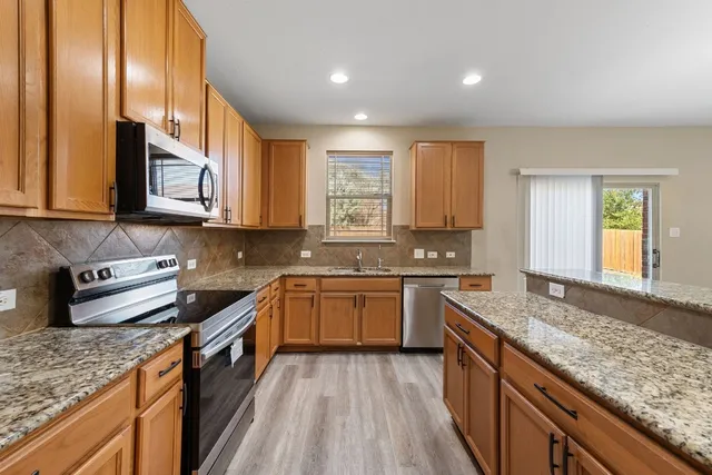 a kitchen with stainless steel appliances granite countertop wooden cabinets granite counter tops and a stove