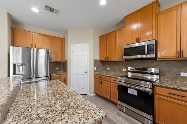 a kitchen with stainless steel appliances granite countertop a stove a refrigerator and a microwave