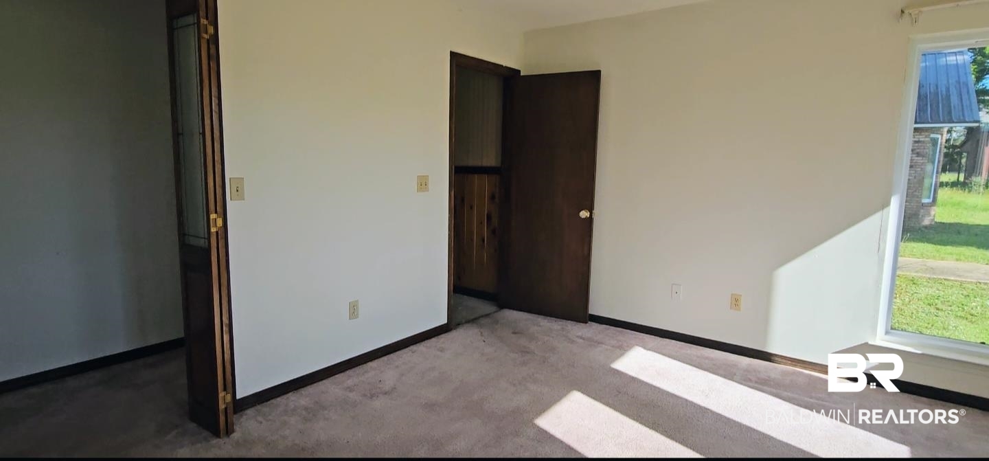 18824 Highway 41 Brewton, AL 36426 - Photo 40 of 40 Carpeted room with white walls, dark wood-finish trim, and a window with white framing