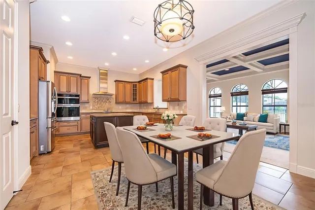 a dining room with stainless steel appliances kitchen island granite countertop a dining table chairs and a refrigerator