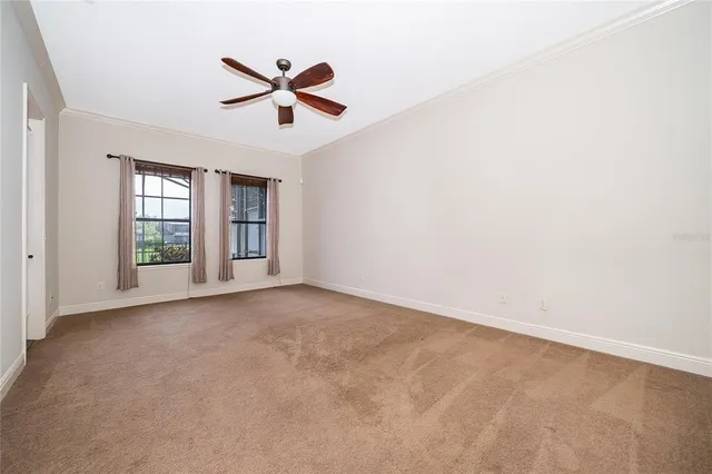 an empty room with ceiling fan and windows