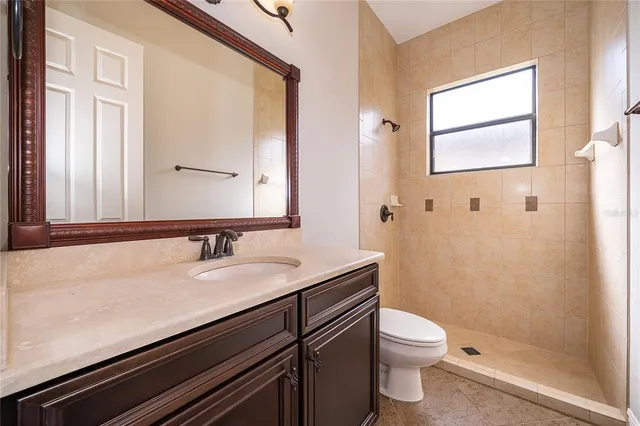 a bathroom with a granite countertop toilet sink and mirror