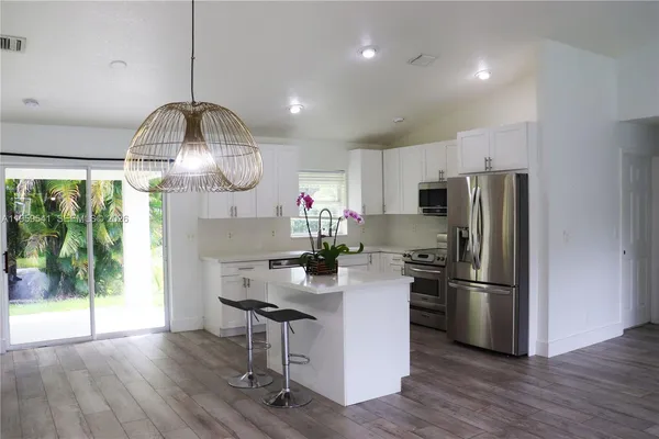 a kitchen with stainless steel appliances a refrigerator sink and wooden floor