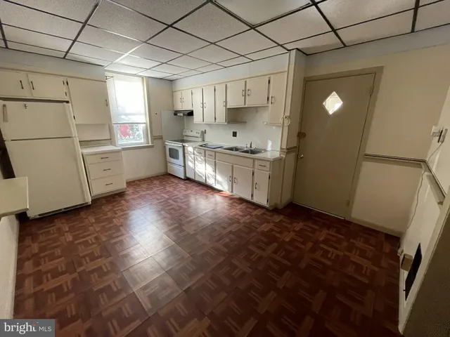 a kitchen with a sink a stove cabinets and wooden floor