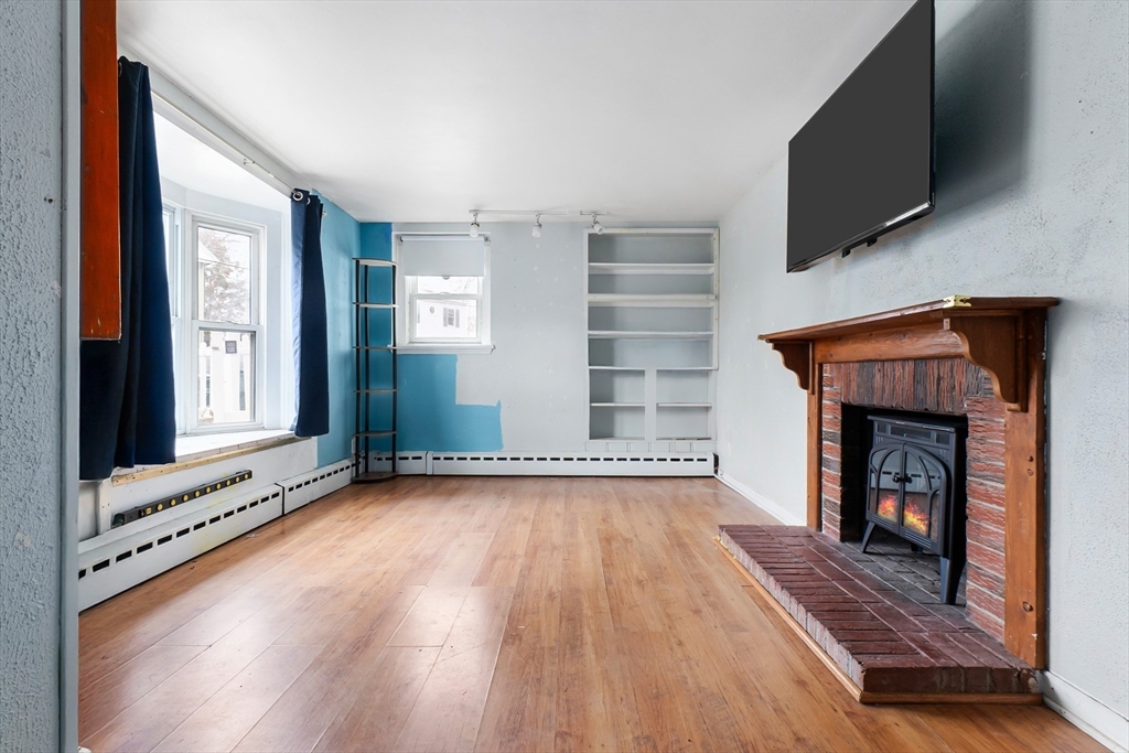 159 Jenness Street Lynn, MA 01904 - Photo 17 of 36 a view of an empty room with wooden floor fireplace and a window