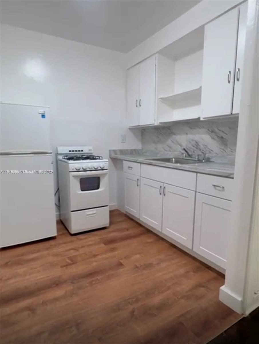 a kitchen with granite countertop white cabinets and white appliances