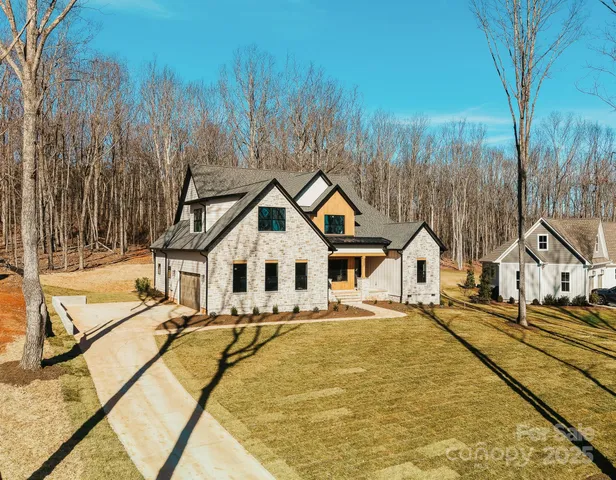 a view of a white house with a large pool and couches chairs