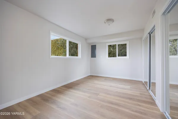 a view of an empty room with wooden floor and a window