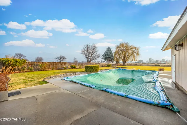 a view of house with backyard and bushes