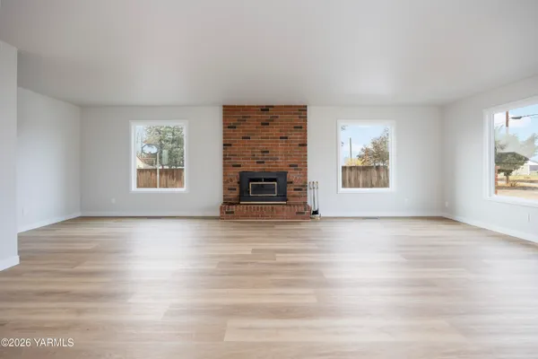 a view of an empty room with window and fire place