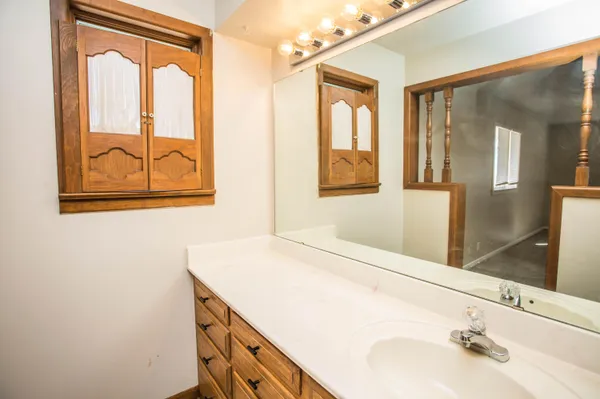 a view of a hallway with wooden floor and a bathroom