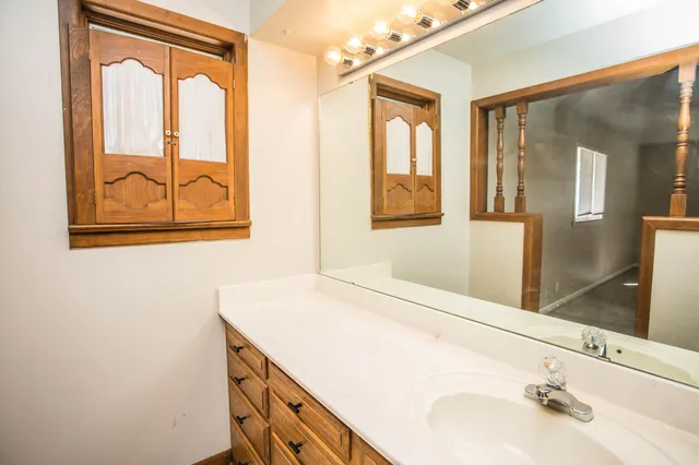 a view of a hallway with wooden floor and a bathroom