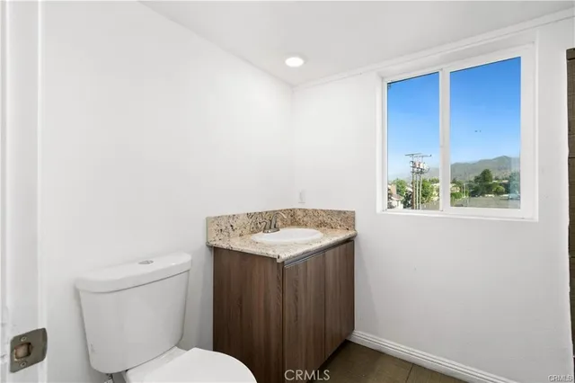 a bathroom with a granite countertop sink and a toilet