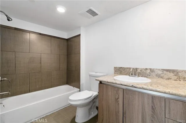 a bathroom with a granite countertop bathtub sink vanity mirror and toilet