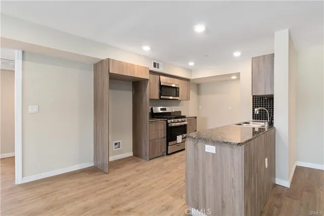 a kitchen with stainless steel appliances granite countertop a refrigerator and a stove top oven