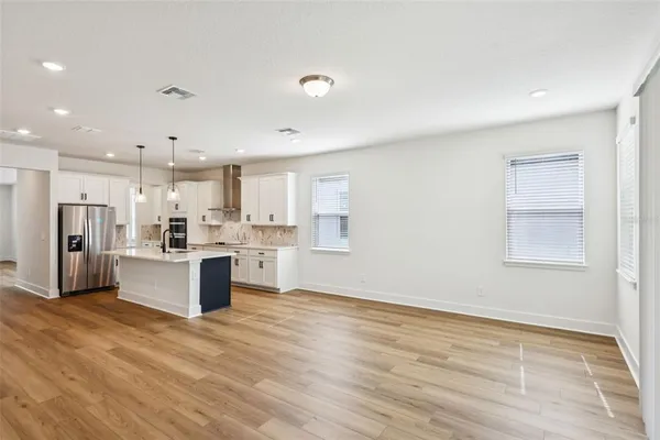a view of kitchen with stainless steel appliances granite countertop a stove top oven a sink dishwasher a refrigerator and white cabinets with wooden floor