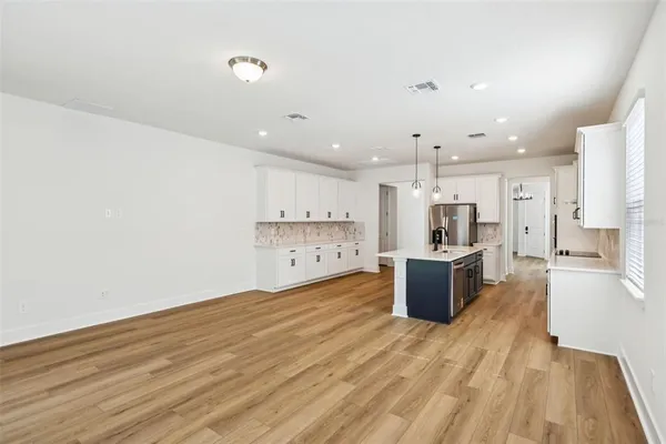 a large kitchen with a wooden floor and stainless steel appliances