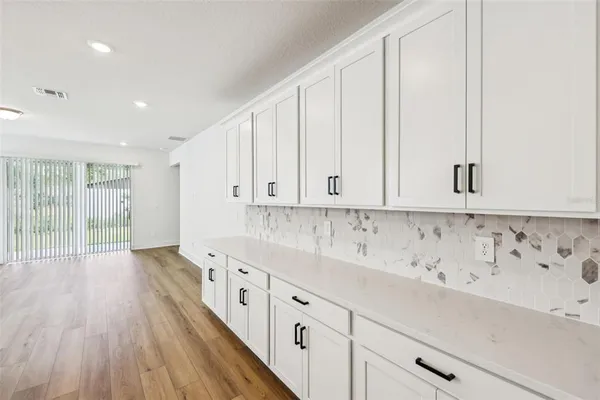 a kitchen with granite countertop a white sink and white cabinets with wooden floor