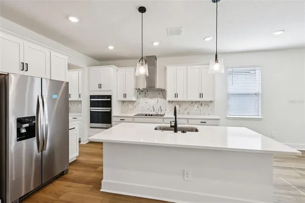 a kitchen with kitchen island a refrigerator a sink and cabinets