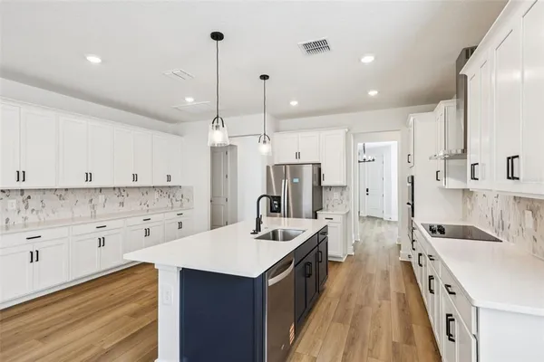 a kitchen with a sink a center island a refrigerator and cabinets