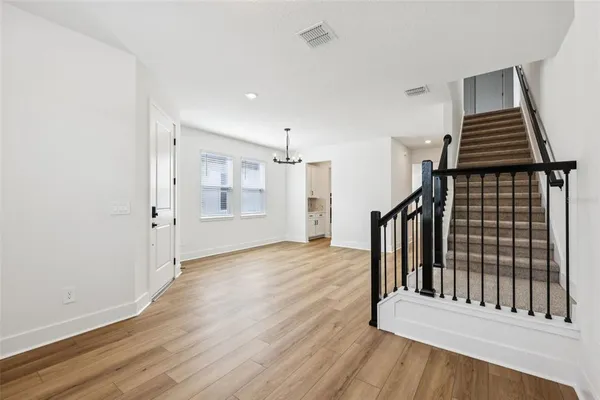 a view of an empty room with wooden floor and stairs