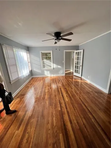a view of empty room with wooden floor and fan