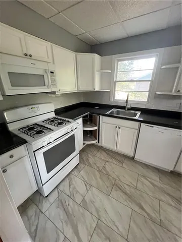 a kitchen with granite countertop a stove a sink and a microwave