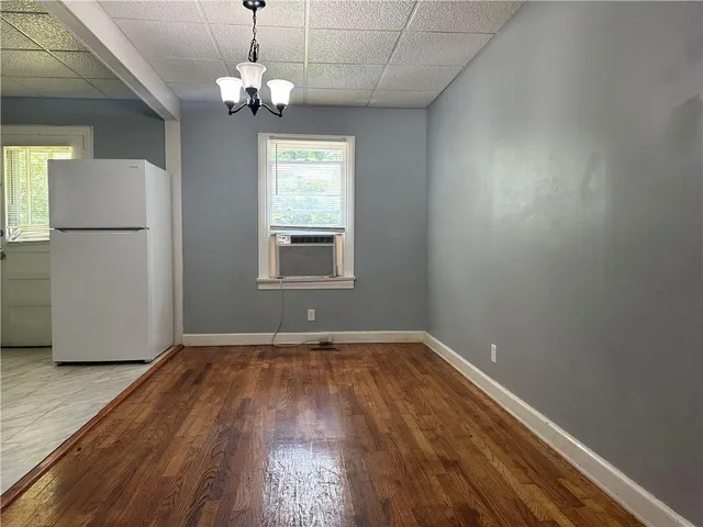 an empty room with wooden floor chandelier and windows
