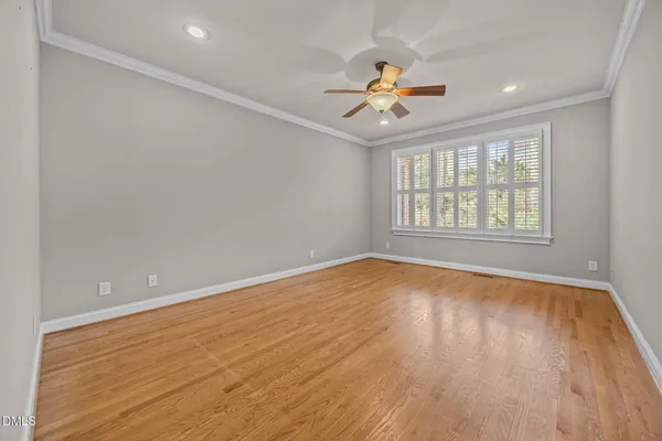an empty room with wooden floor chandelier fan and windows