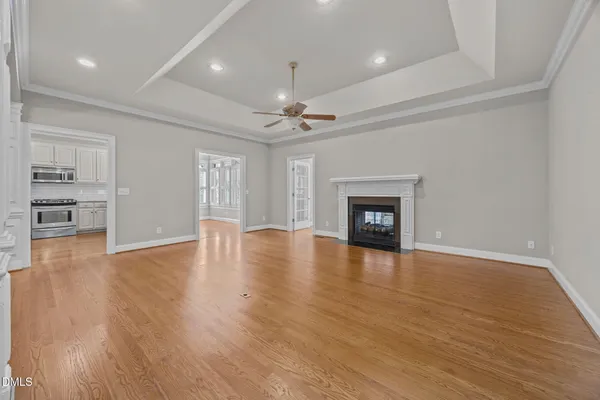 an empty room with wooden floor fireplace and windows