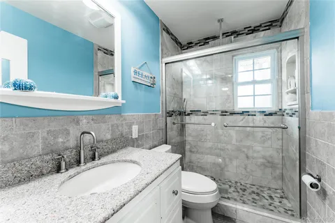 a bathroom with a granite countertop sink toilet and shower
