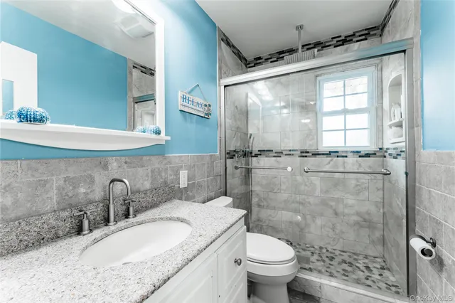 a bathroom with a granite countertop sink toilet and shower