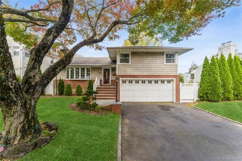 a view of a house with a small yard and a large tree