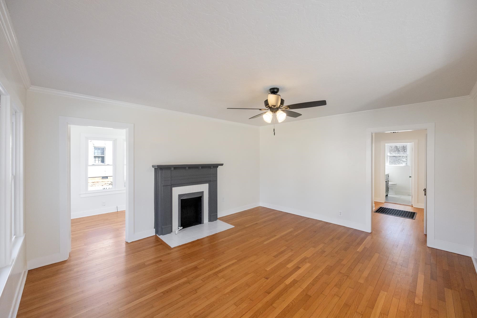 242 Broad Street North Lexington, TN 38351 - Photo 21 of 40 Unfurnished living room featuring ornamental molding, a fireplace with flush hearth, light wood-type flooring, and ceiling fan